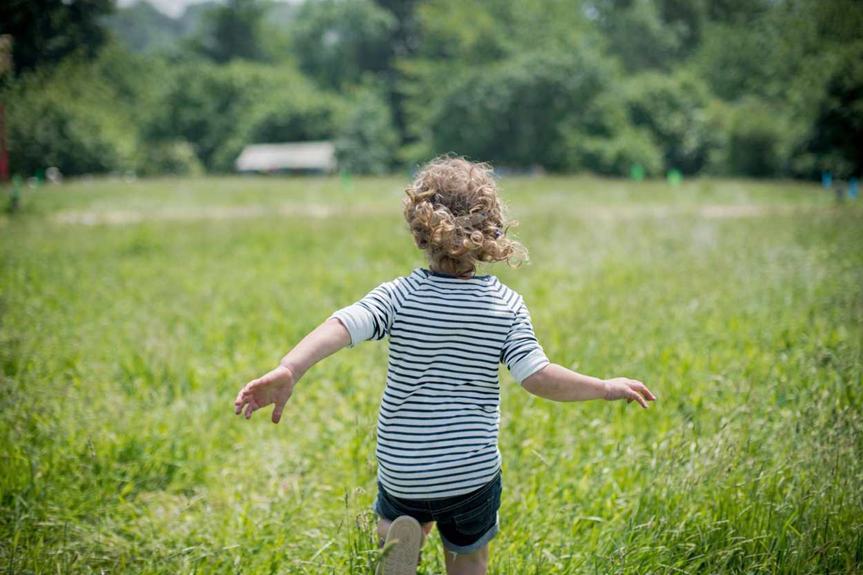 Child Running Through A Green Field